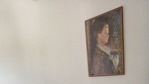 Een knus, klein vertrek met een bruine bank, een witte muur en een lijst met een schilderij.