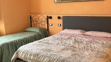 A bedroom with a large bed, two bedside tables, a nightstand, a painting on the wall, and a ceiling light fixture.