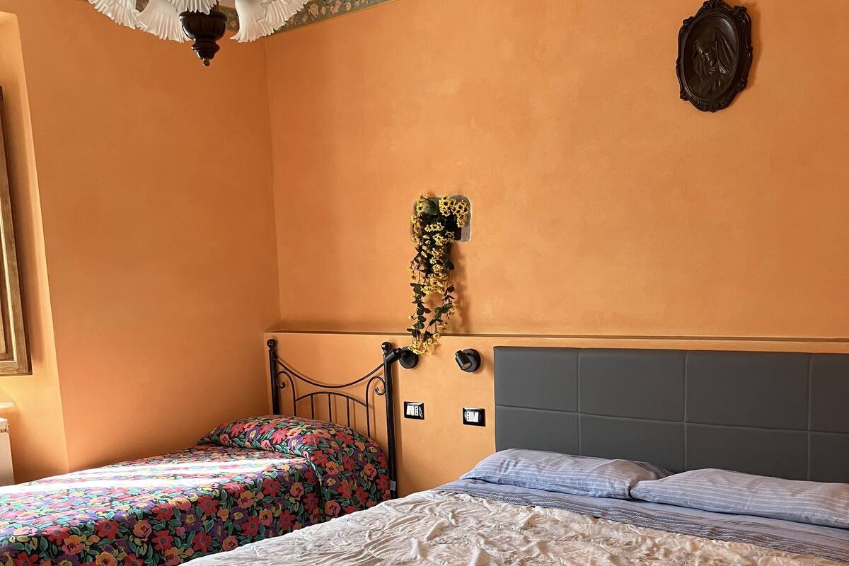 A bedroom with two beds, a chandelier, a floral wall border, and a wall-mounted decoration.