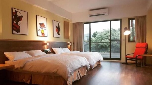 Une chambre d’hôtel avec un grand lit, une chaise et une vue sur les arbres par la fenêtre.