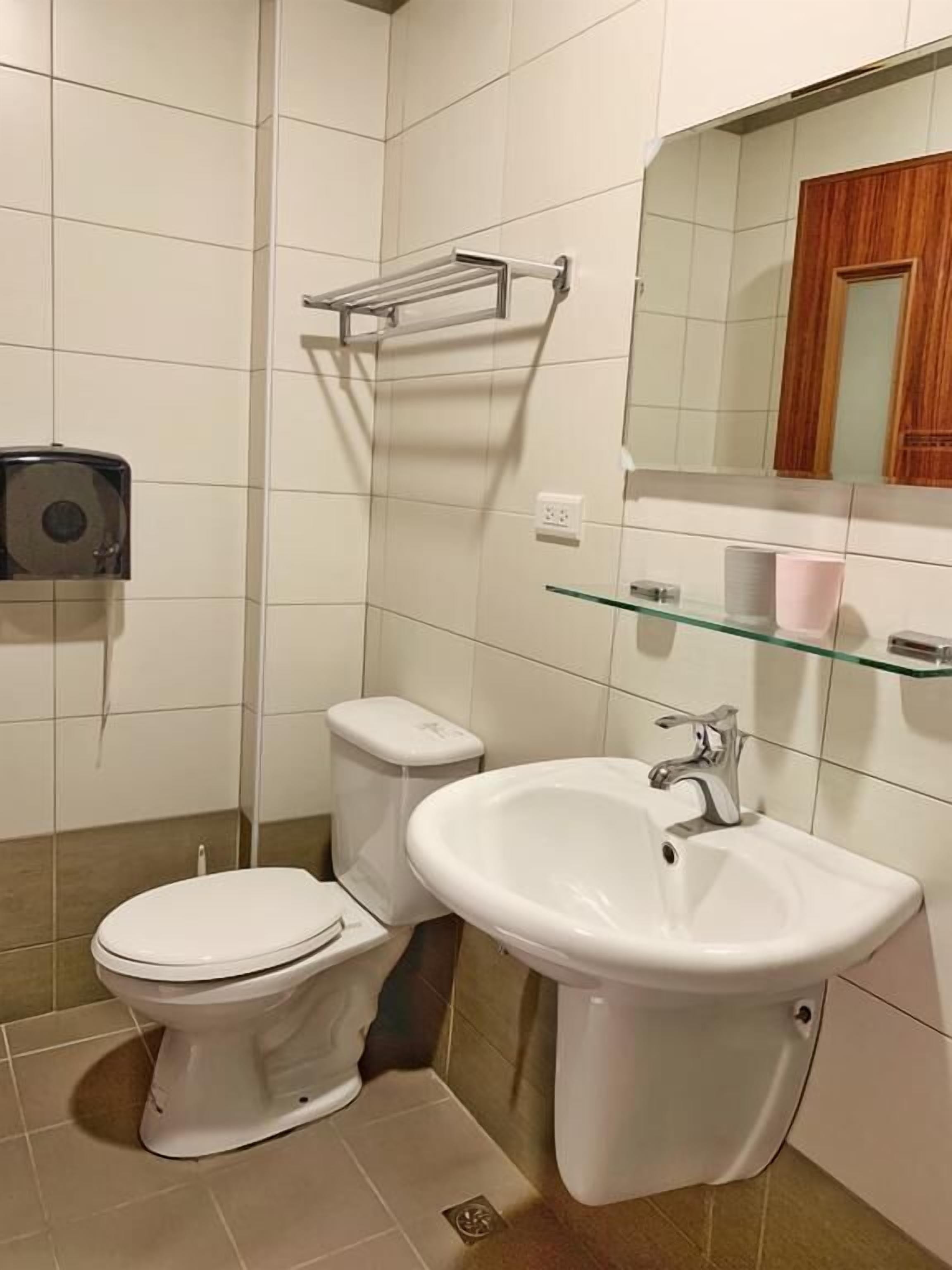 Un baño con inodoro, lavamanos y secamanos.