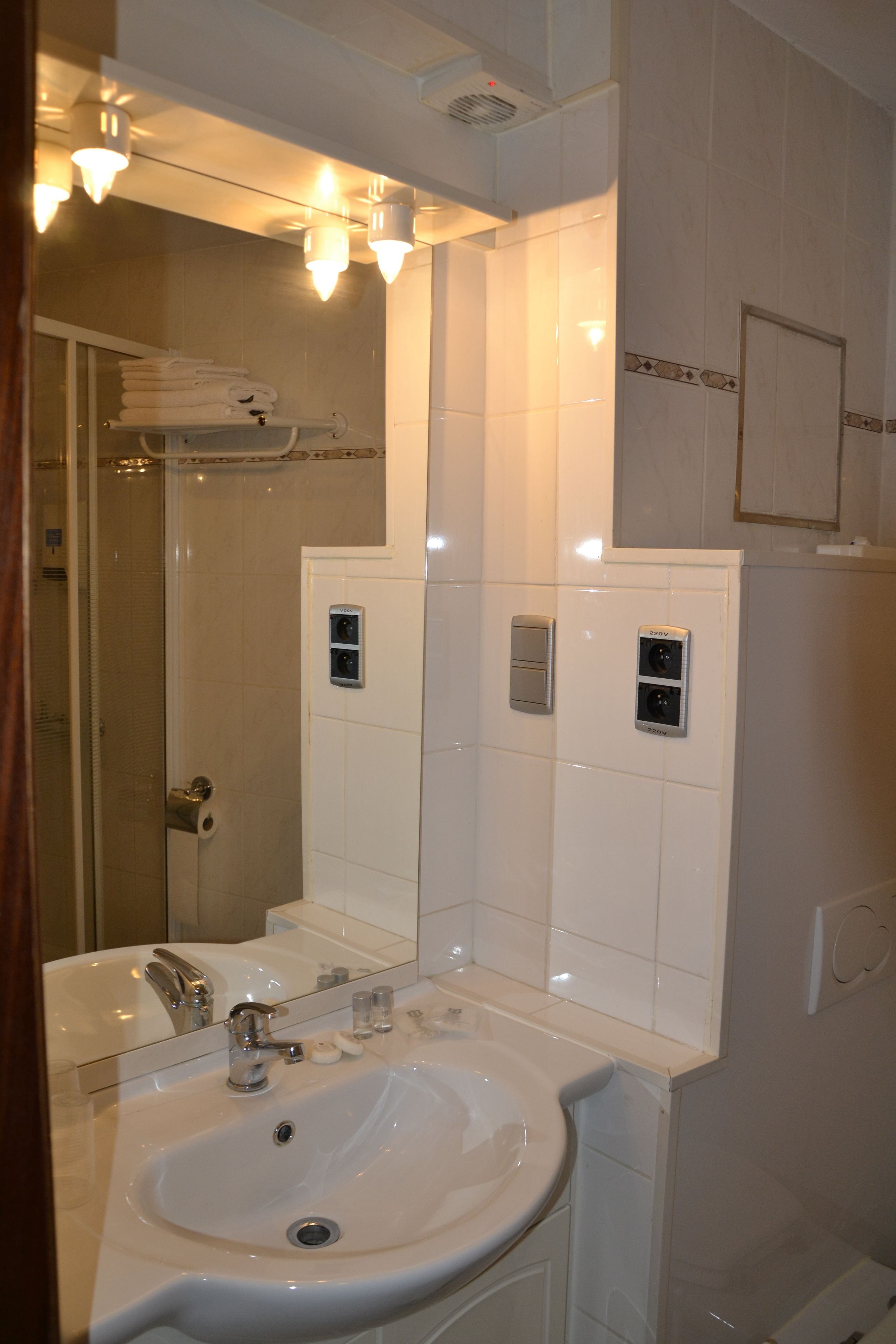 A bathroom with a sink, mirror, towel rack, and a shower area.