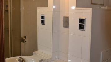 Un baño con lavamanos, espejo, toallero y zona de ducha.