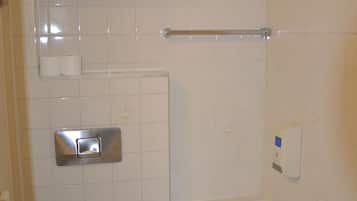 A bathroom with a toilet, a bathtub, a towel rack, and a soap dispenser.
