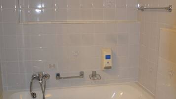 A bathroom with a bathtub, toilet, and hand sanitizer dispenser.