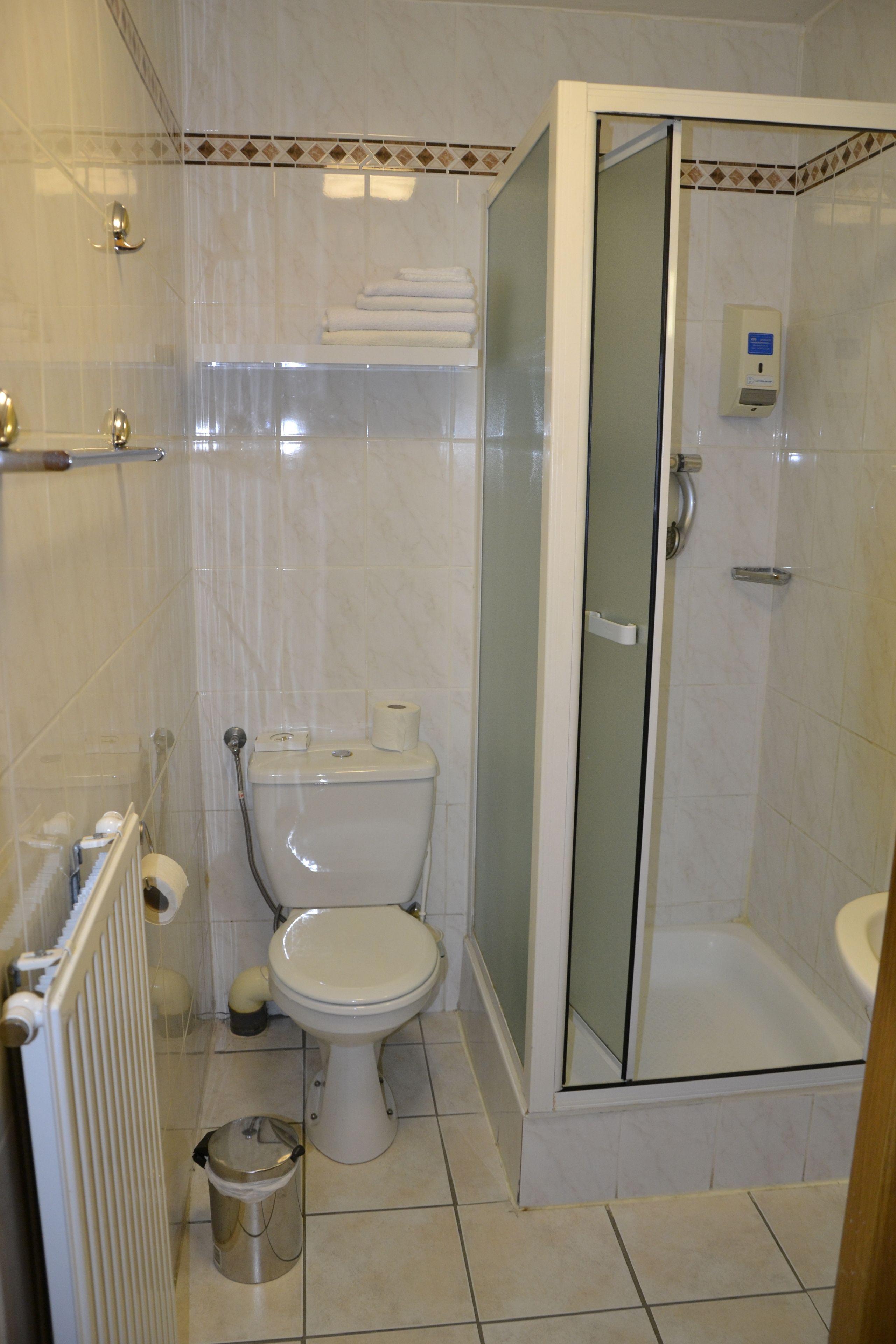 Un baño con inodoro, cabina de ducha y radiador.