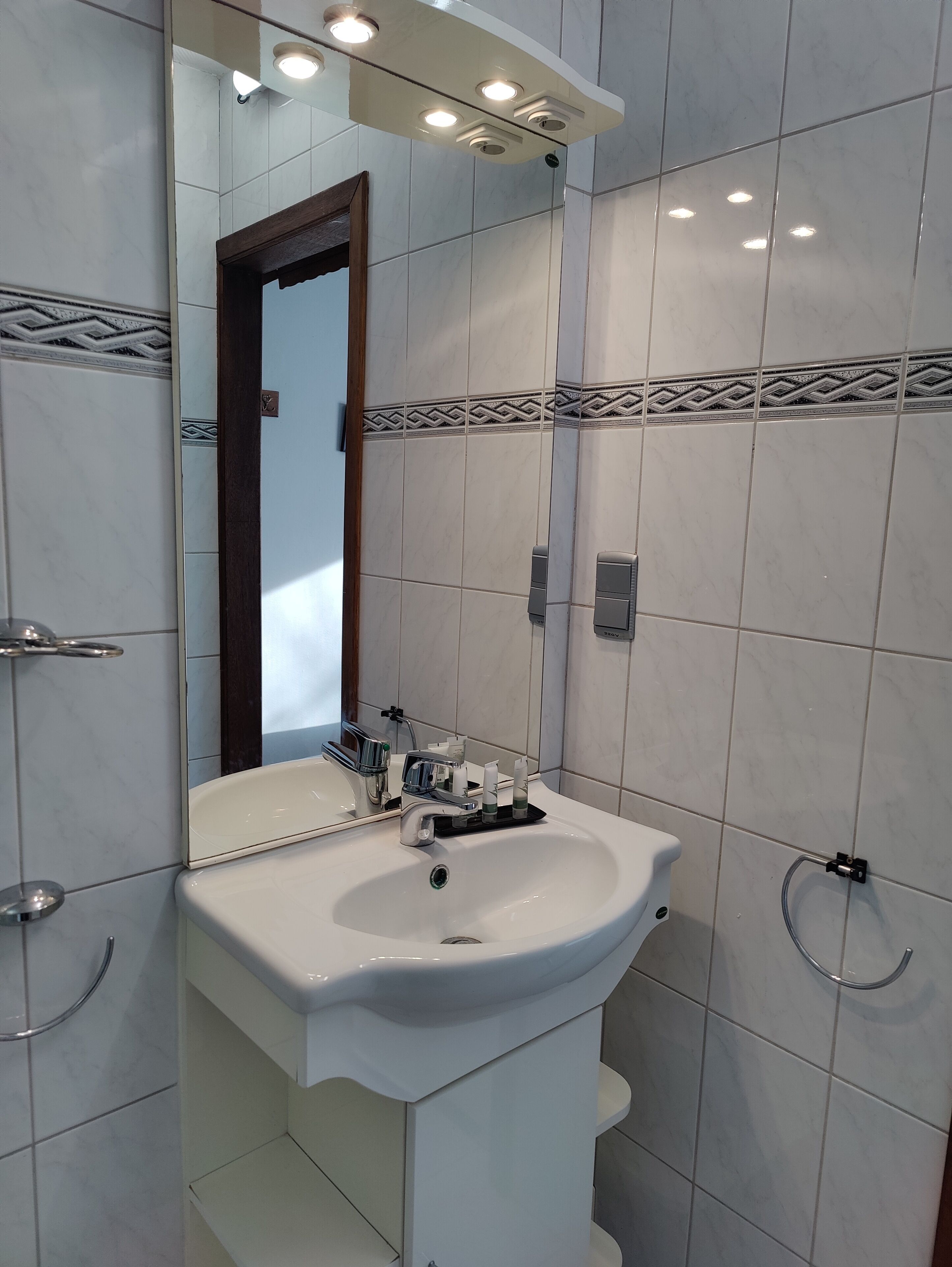 Un baño con lavamanos blanco, espejo y ducha.