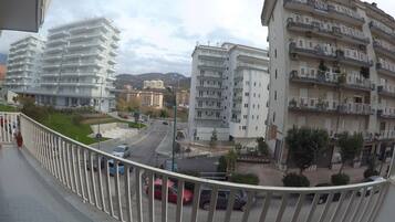 Un edificio moderno con diversi balconi, un'area di parcheggio e vista sul paesaggio urbano circostante.