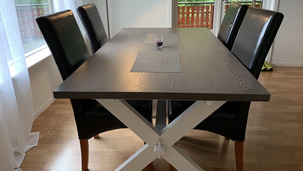Una mesa de comedor con diseño de travesaño, rodeada de sillas negras.