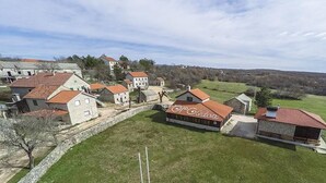 Il s’agit d’une propriété rurale comprenant plusieurs bâtiments, notamment une maison principale avec un toit rouge et une grange.