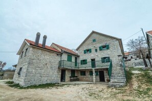 A two-story stone house with a balcony and a small porch.