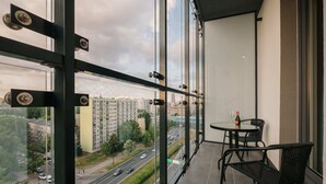 A balcony with a view of a cityscape, a round table with chairs, and a bottle of champagne. - Varsovia Comfort Studios (Warsaw)