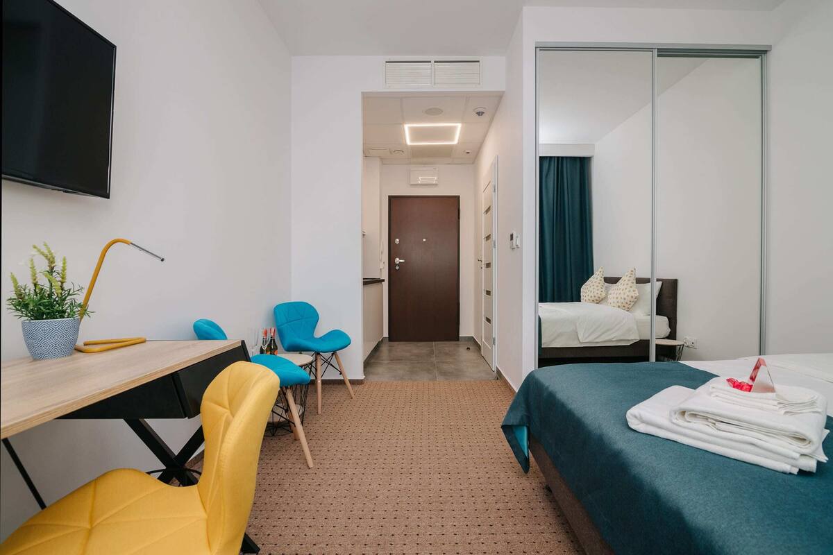Une chambre d’hôtel avec un lit, un bureau et une chaise, une télévision et une salle de bain visible à travers une porte ouverte.