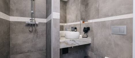 A modern bathroom with a shower, sink, and toilet.