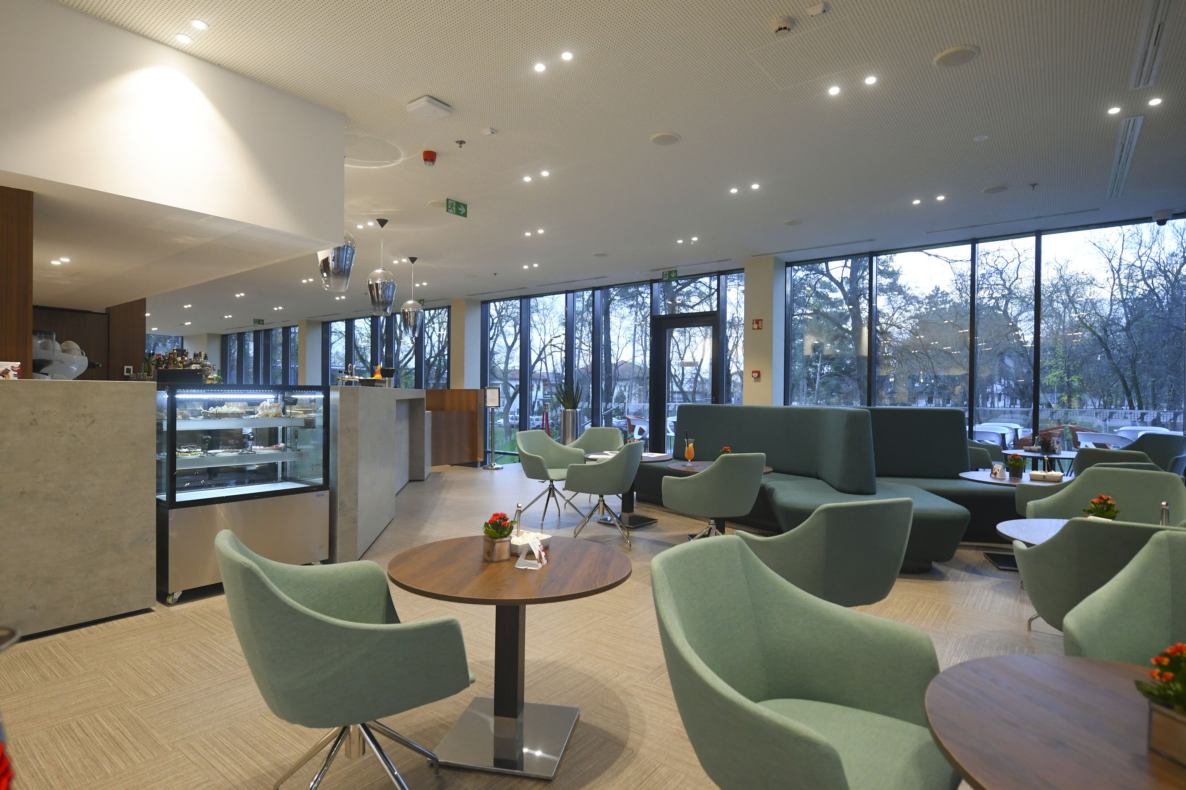 A modern interior with seating areas, a counter, and large windows offering a view of the outdoors.