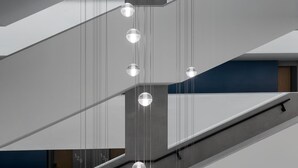 A modern interior with a staircase and hanging spherical light fixtures. - Hunguest Hotel Sóstó (Nyiregyhaza)