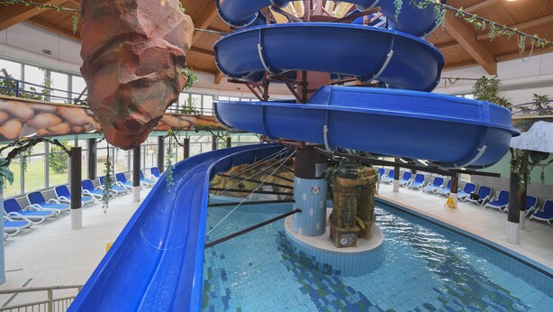 An indoor water slide with multiple levels and a pool area with lounge chairs. - Hunguest Hotel Sóstó (Nyiregyhaza)