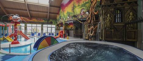 An indoor swimming pool with slides and a hot tub.