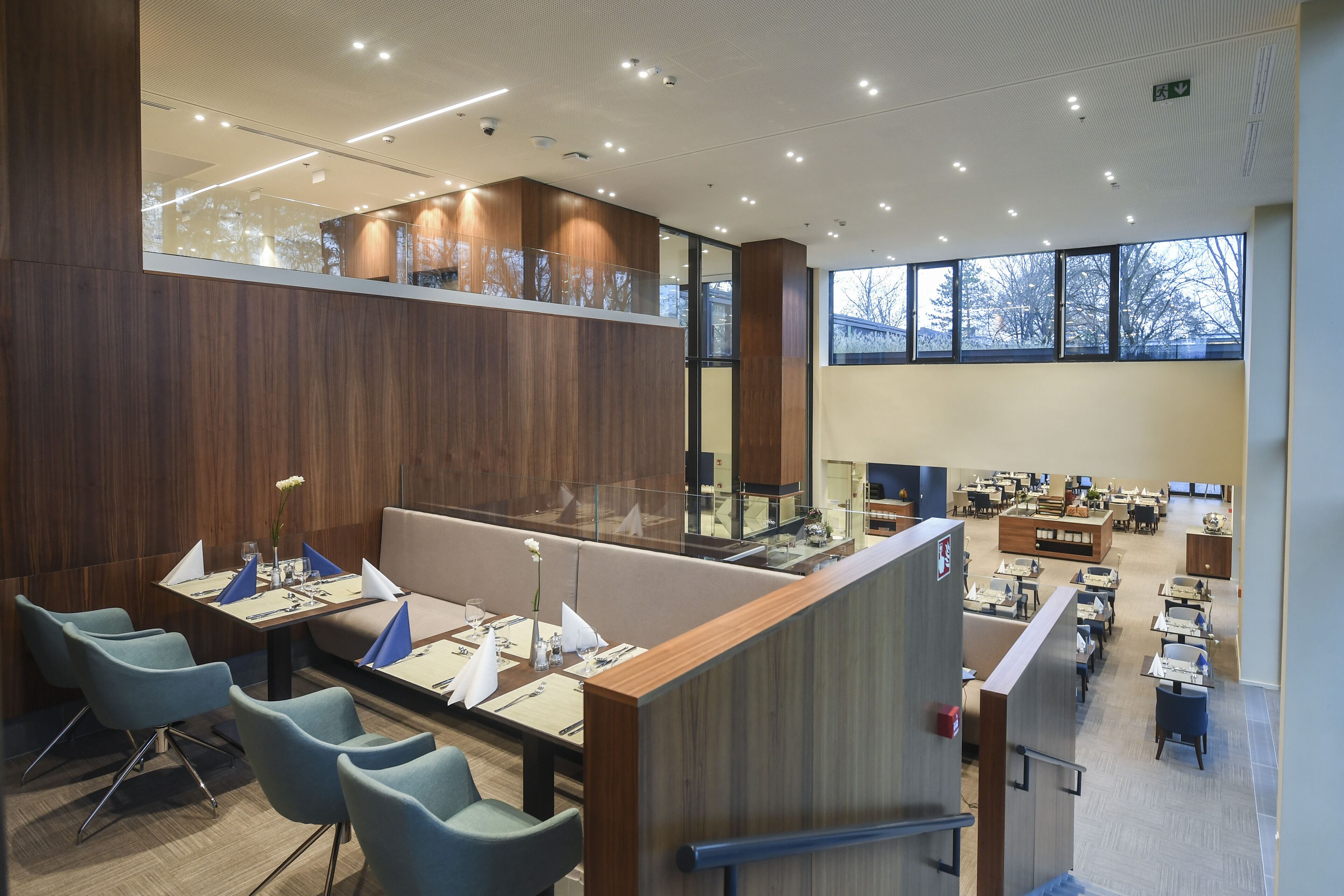 A modern dining area with high tables, comfortable seating, and large windows providing natural light.
