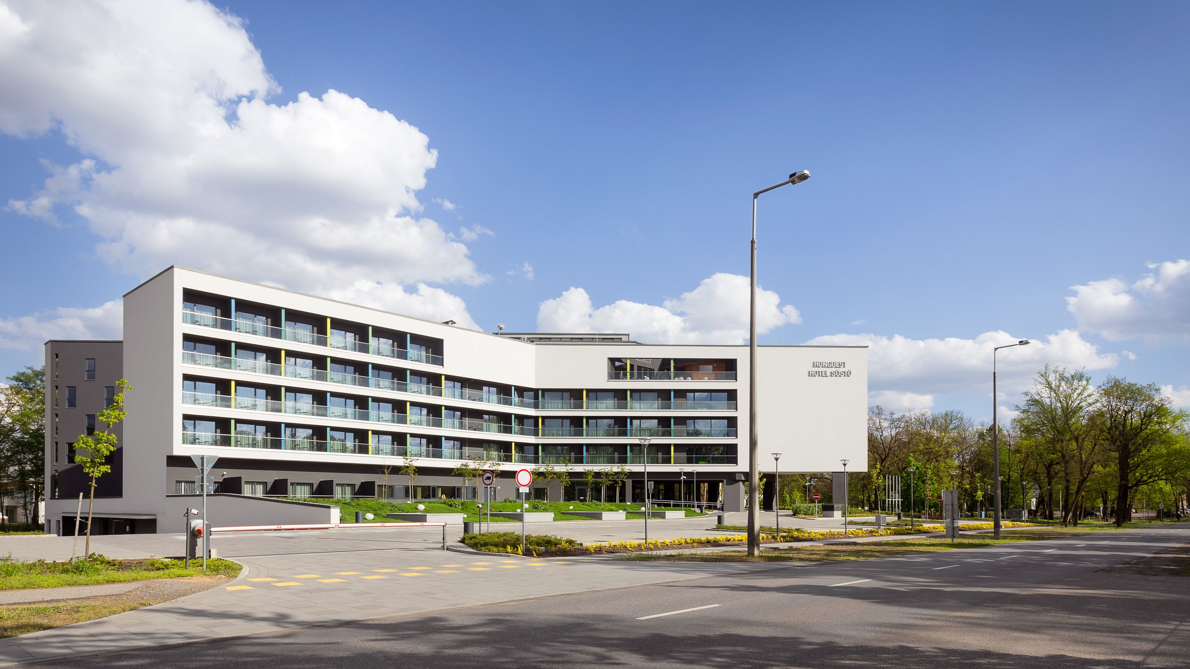 A modern multi-story building with a flat roof, large windows, and a sign indicating it is a hotel.