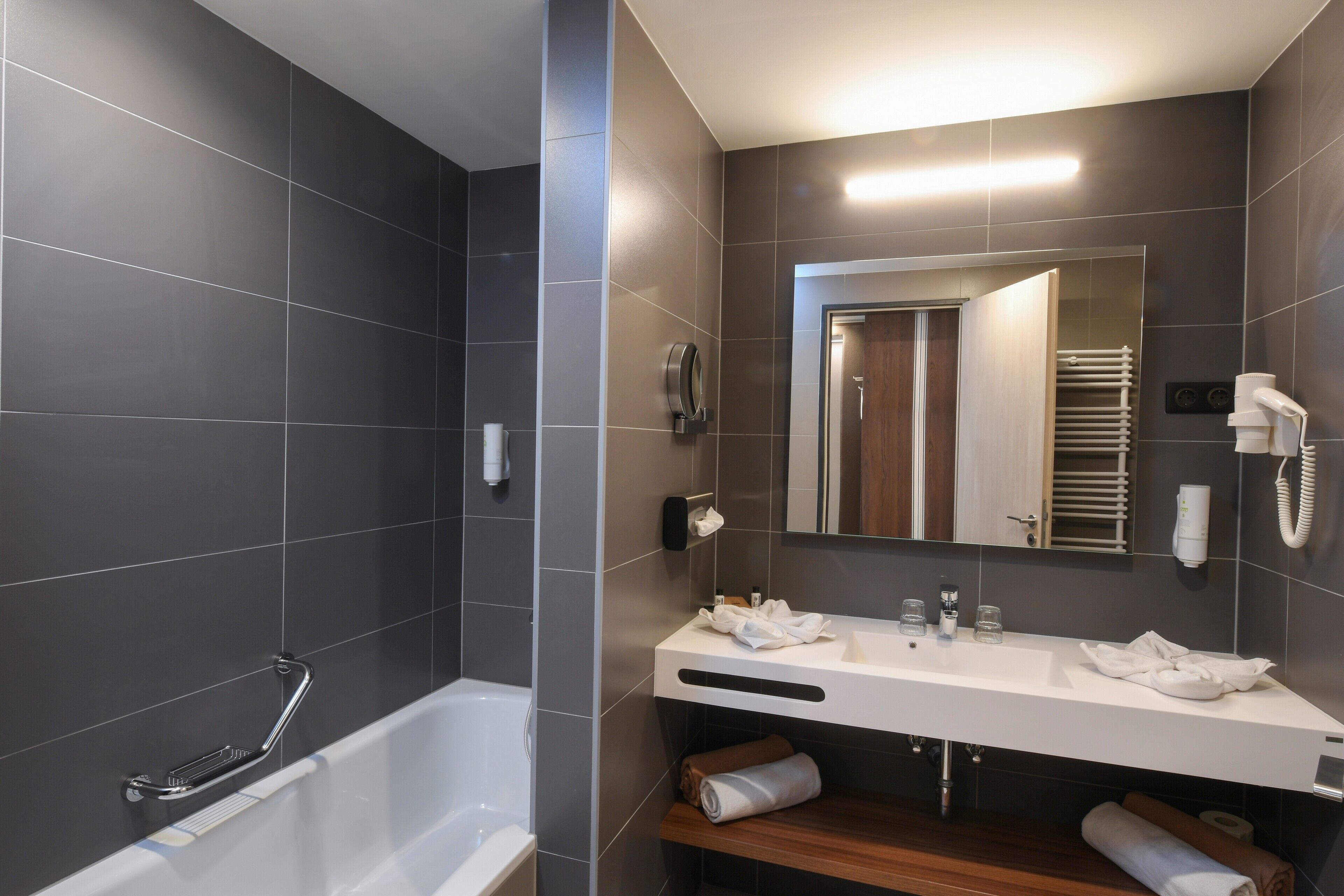Un baño moderno con una bañera, un tocador con espejo y un perchero para toallas.