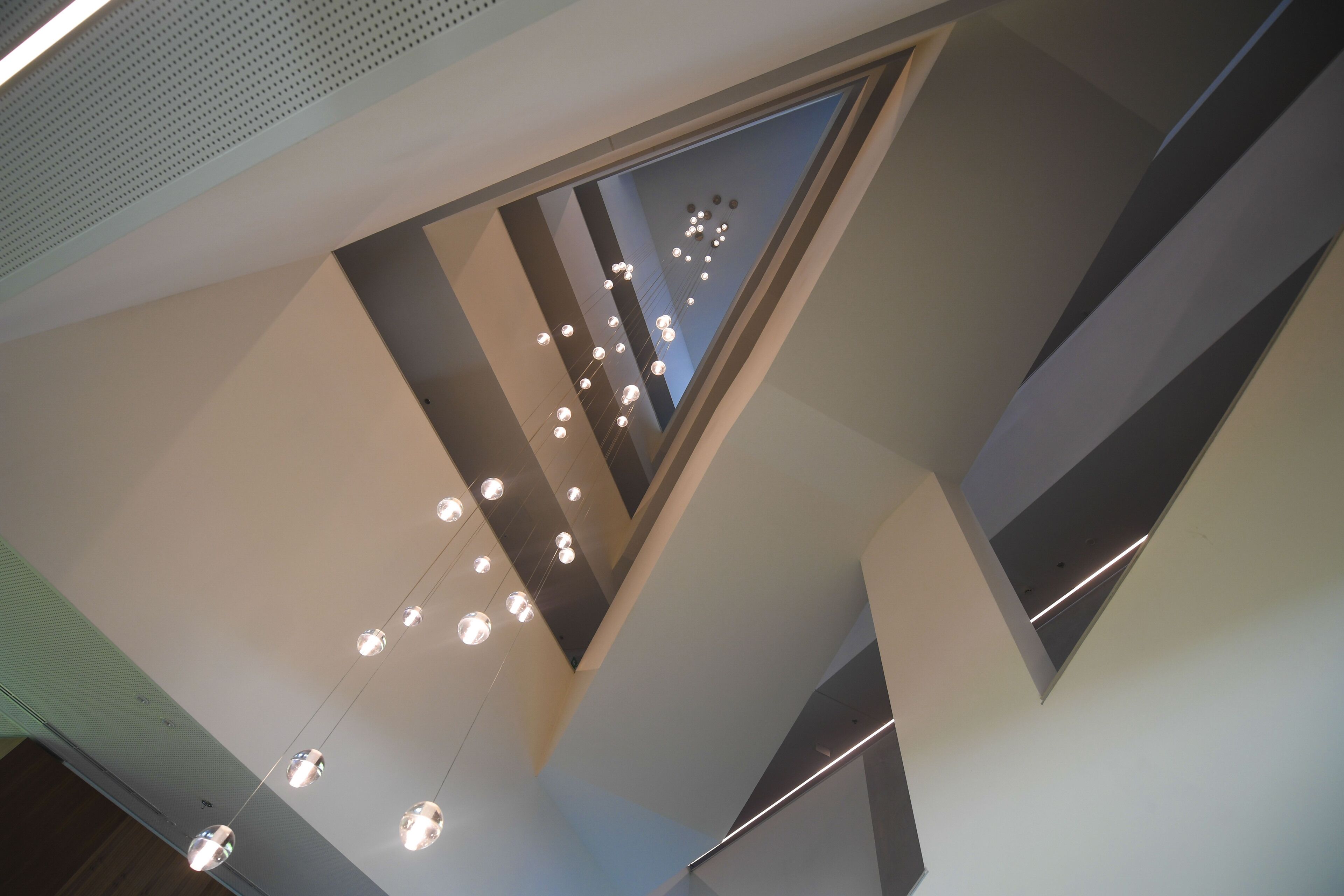 Un interior moderno con techo alto, iluminación empotrada y vistas a través de un panel de vidrio.