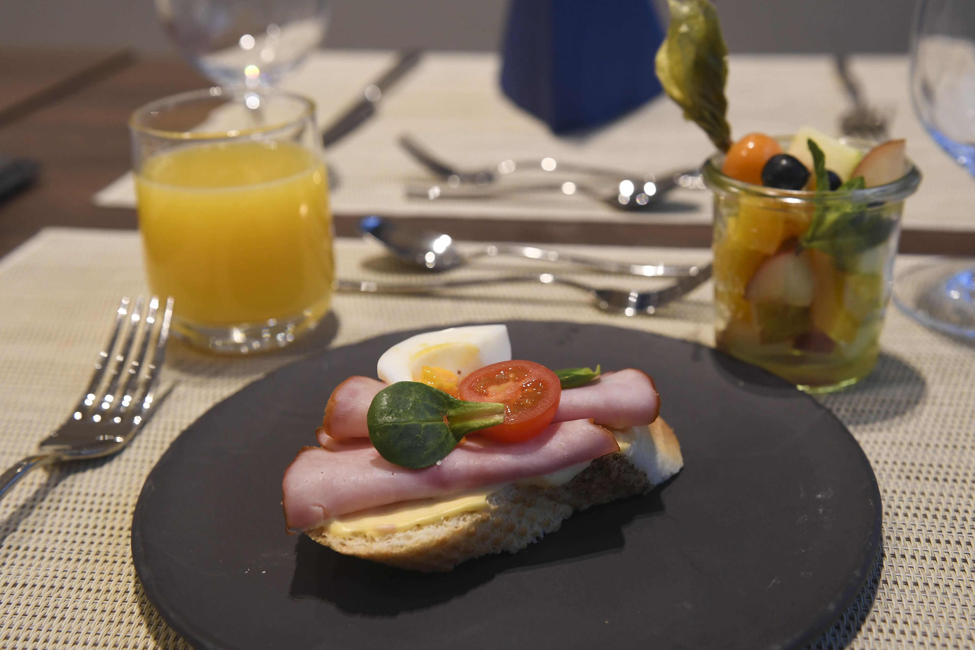 A breakfast setting with a plate of food, a glass of orange juice, and a fruit salad.