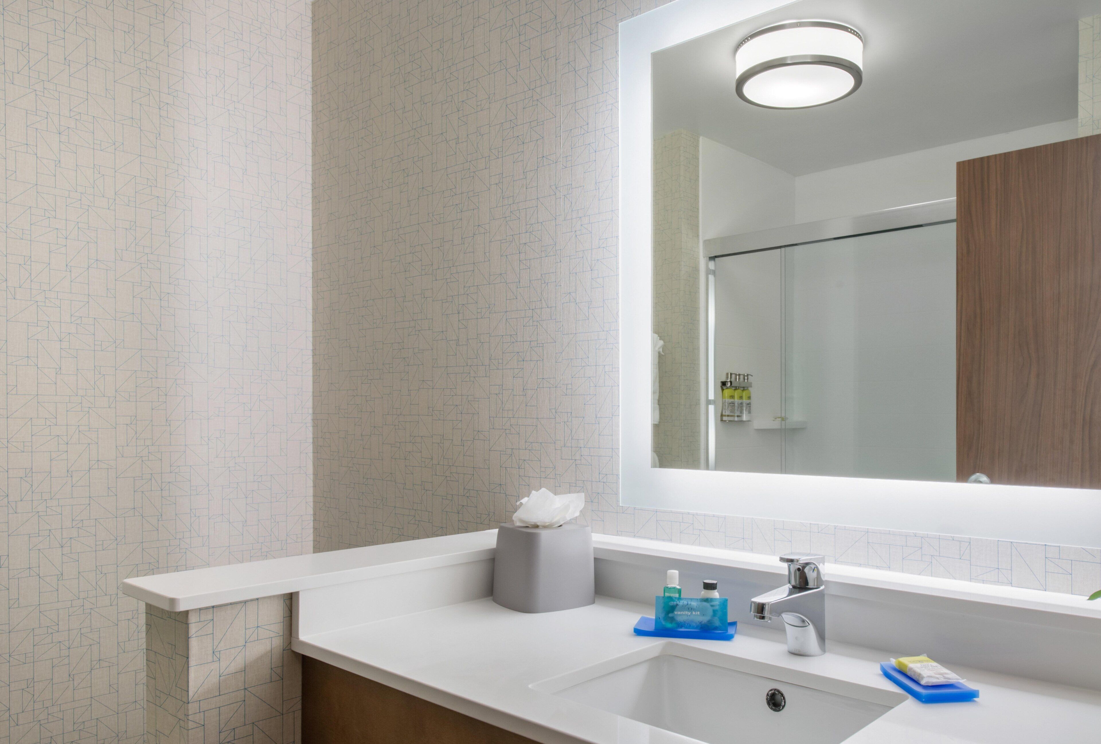 A modern bathroom with a white sink, a mirror, and a vanity area.
