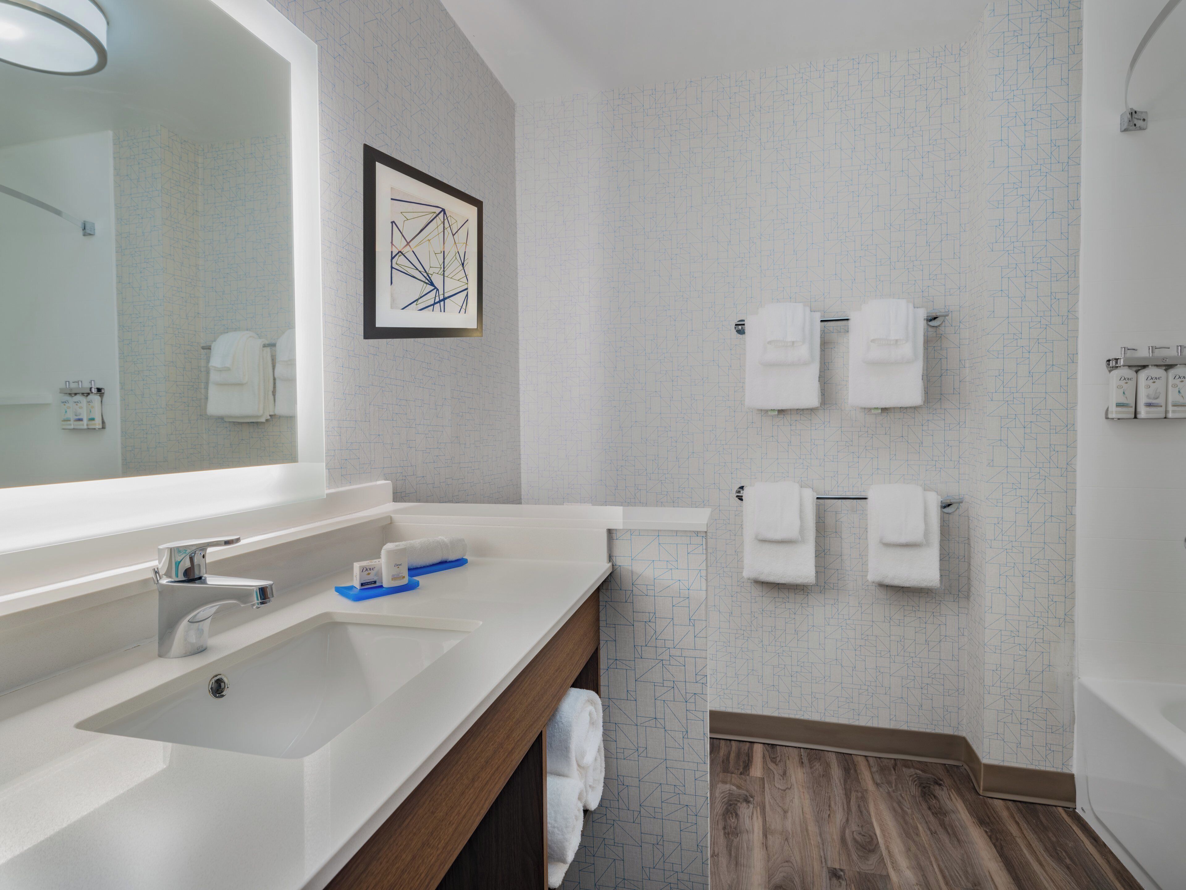 Un baño moderno con un espejo grande, un lavabo, una bañera y una ducha.