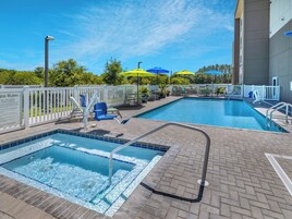 Una piscina al aire libre, sombrillas, sillones reclinables de piscina