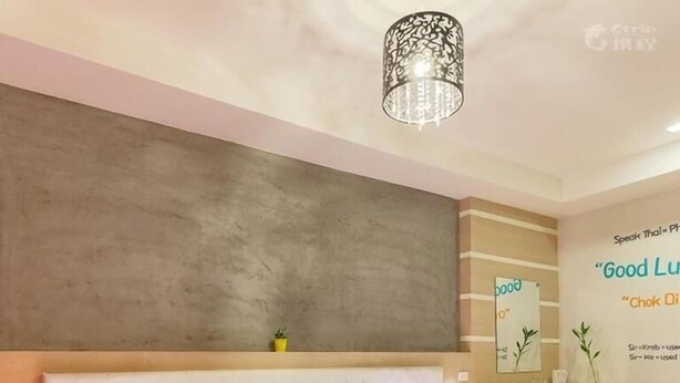 A modern bedroom with a tufted headboard, a large bed with a blue bedspread, bedside lamps, and a decorative ceiling light. - Small Shells Hotel Phuket (Patong)