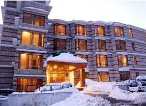 A multi-story hotel with a snow-covered entrance and illuminated windows.