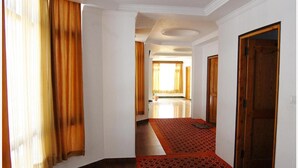 Un pasillo con alfombra estampada, puertas de madera y vistas a una habitación con un gran ventanal y cortinas.