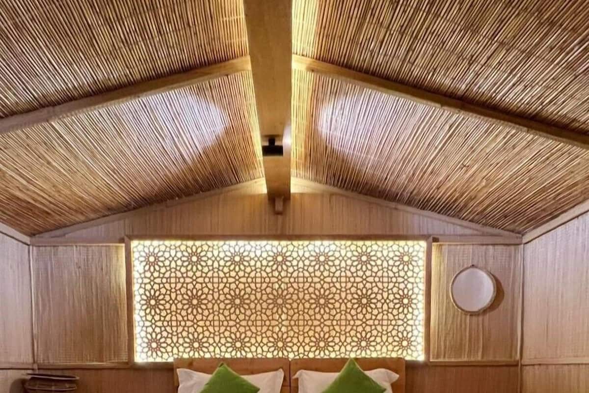 A bedroom with a high, sloped ceiling and a decorative wooden panel wall.