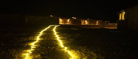 Una vista nocturna de un edificio con un sendero iluminado por luces amarillas que conduce a la entrada.