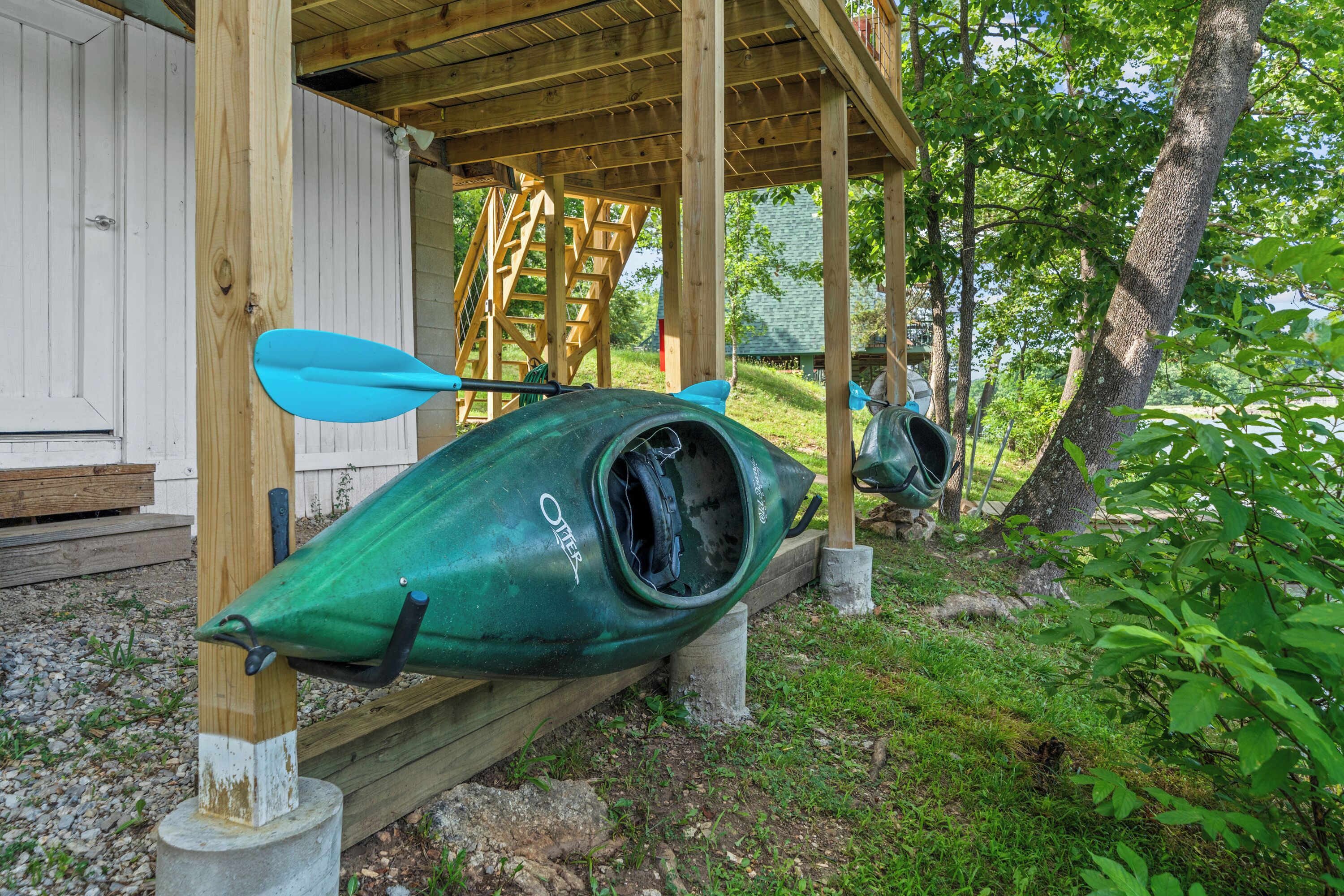 A kayak and paddle leaning against a wooden structure.