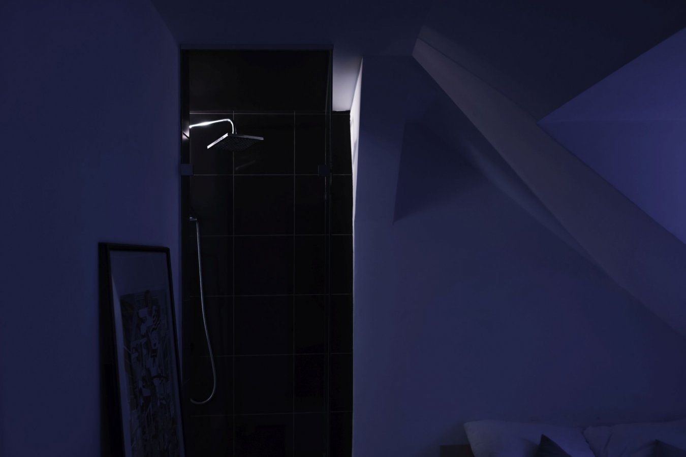 Un bagno dalle tonalità scure con doccia, una cornice appesa al muro e una finestra.