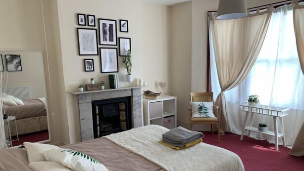 A bedroom with a bed, a fireplace, a desk, and a chair. - London Walthamstow Home (London)