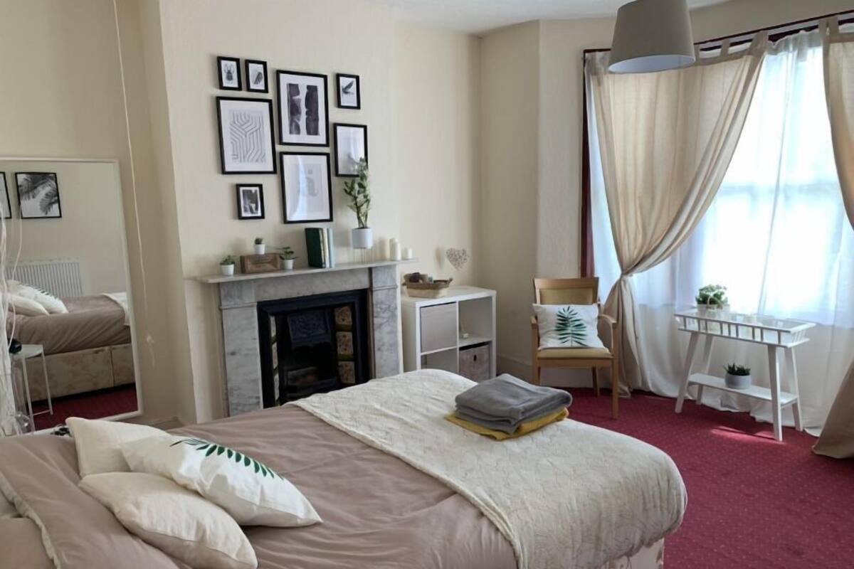 A bedroom with a bed, a fireplace, a desk, and a chair.