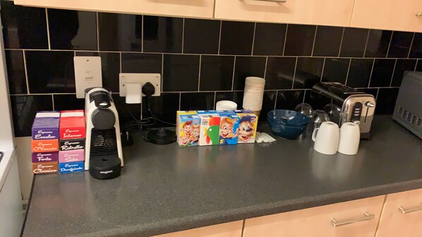 A kitchen counter with various items including cereal boxes, a coffee maker, a toaster, and a blender.