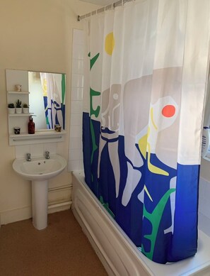A bathroom with a white pedestal sink, a mirror above it, and a shower curtain with abstract designs. - London Walthamstow Home (London)