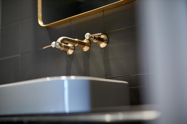 Un baño con grifo dorado y un lavamanos moderno.