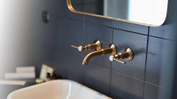 Un baño con un lavamanos blanco, un grifo dorado y un espejo con marco dorado.