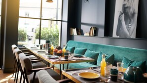 Un comedor con una mesa larga, sillas, un sofá y un ventanal grande.