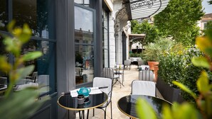 Un espacio exterior con mesas y sillas, una pérgola y plantas en macetas.