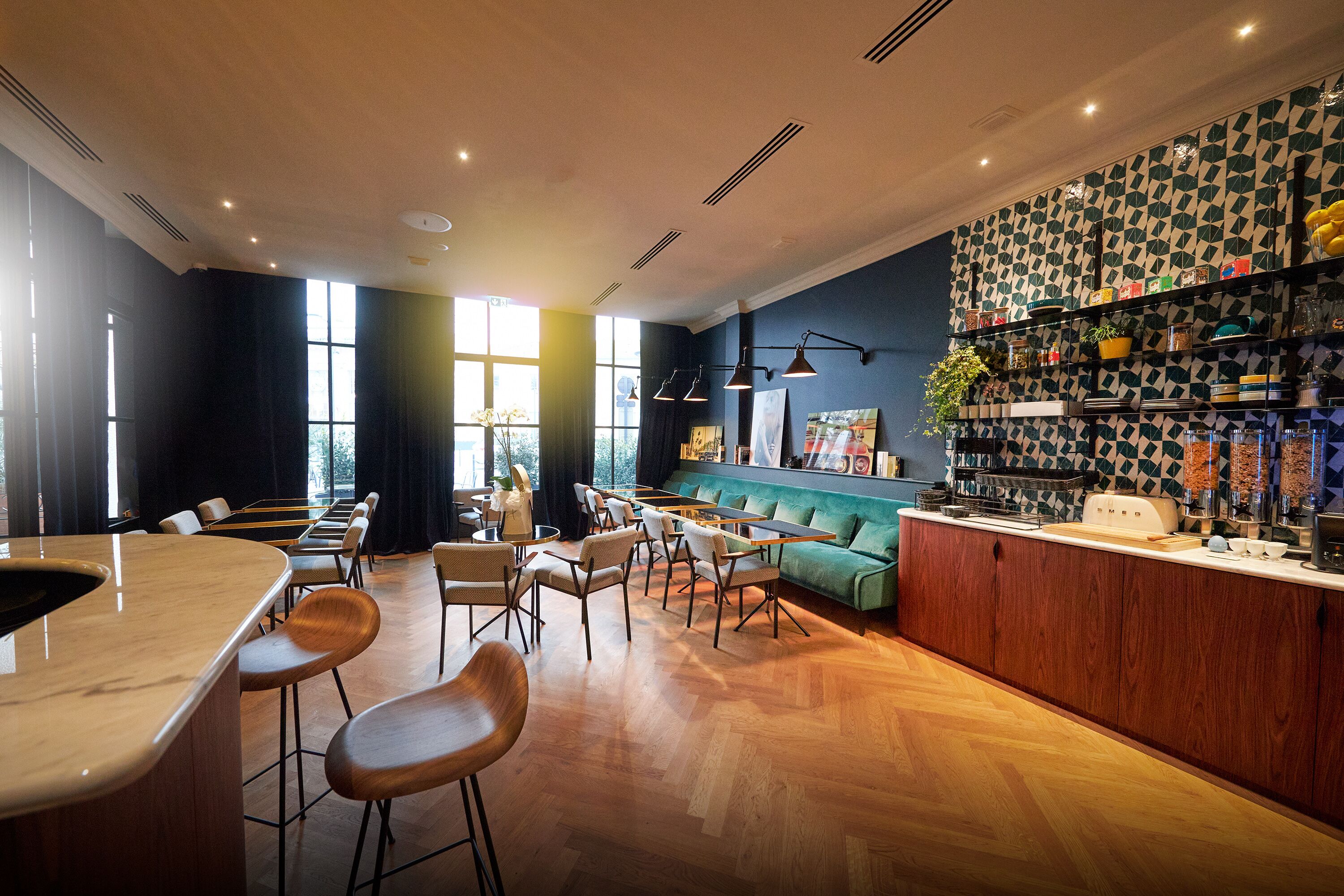 Un restaurante moderno con una zona de bar, suelo de madera y un sofá verde.