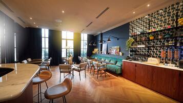Un restaurante moderno con una zona de bar, suelo de madera y un sofá verde.