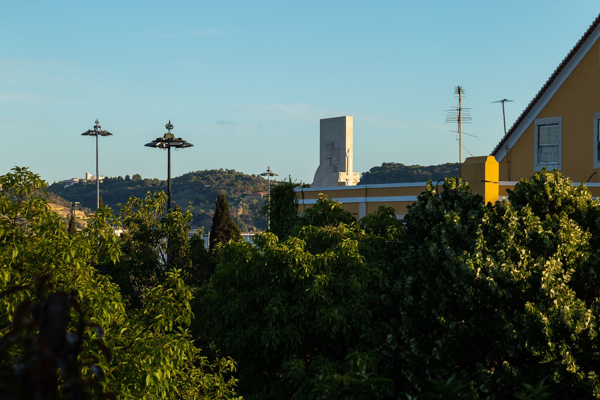 A building with a tall central tower, surrounded by greenery and street lamps.