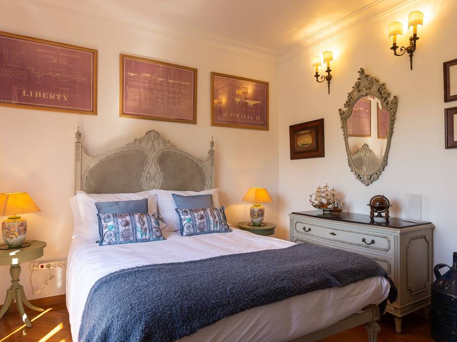 Un dormitorio con una cama grande, dos mesitas de noche con lámparas, un aparador y luces en la pared.