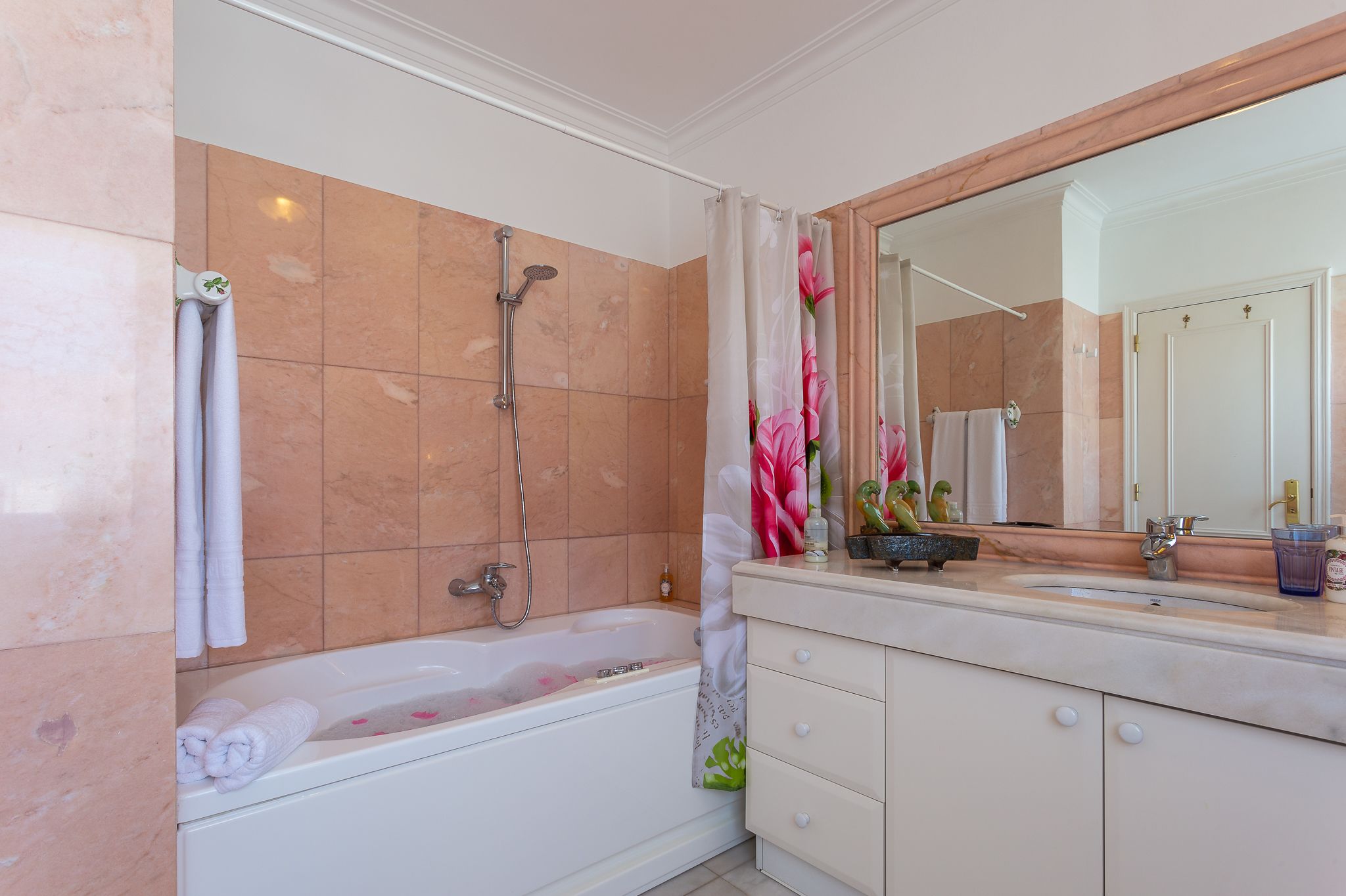 A bathroom with a bathtub, a shower, a sink, and a mirror.